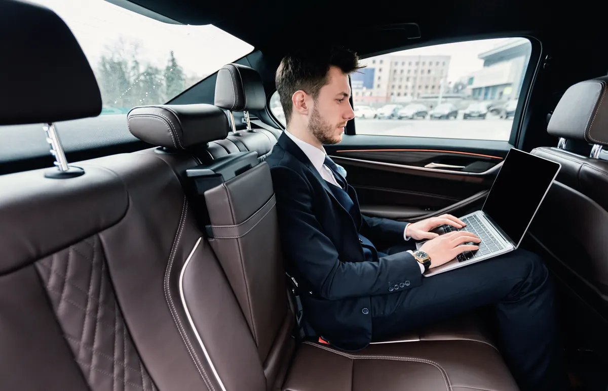 Homme d'affaires travaillant sur son ordinateur portable à l'arrière d'une voiture