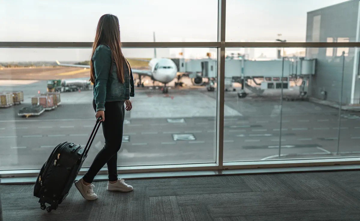 Voyageuse avec valise dans le hall d'embarquement de l'aéroport